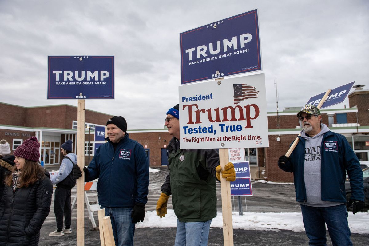 Pendukung Trump memegang tanda selama pemilihan pendahuluan di luar tempat pemungutan suara di Sekolah Menengah Winnacunnet di Hampton, New Hampshire, pada 23 Januari 2024.